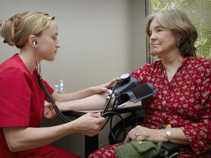 A woman having her blood pressure measured by a nurse