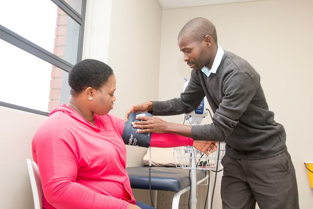 A man fitting a blood pressure cuff to a woman's arm