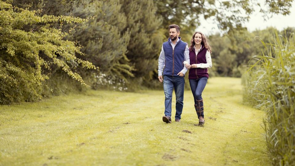A couple walking along a mown path between trees