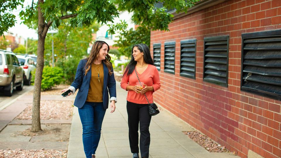 Two friends walking and talking along a street