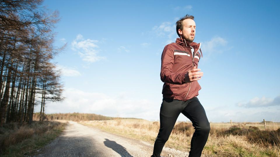 A man running along a moorland track under a blue sky