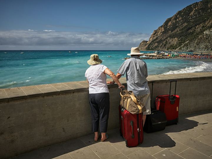 A couple with suitcases looking out over the sea from a harbour wall
